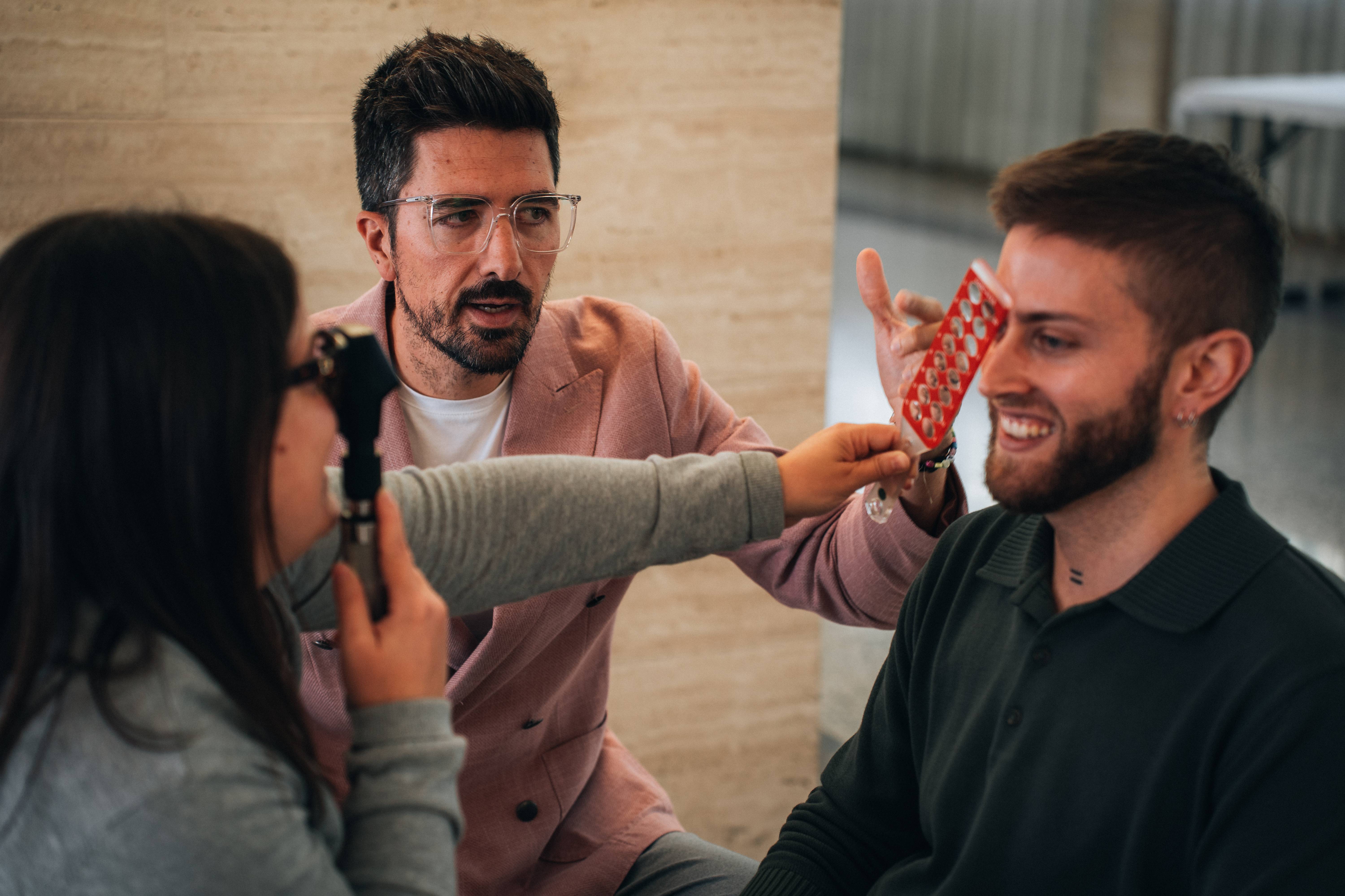 Instructor del Instituto Sanet-Vergara enseñando técnica de exploración ocular a dos alumnos en práctica clínica